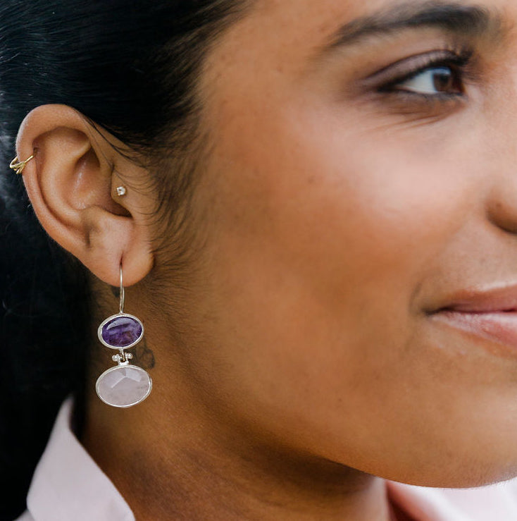 Woman wearing Two Stone Amethyst and Rose Quartz Sterling Silver Earrings with a yellow rose boutonniere on a light background