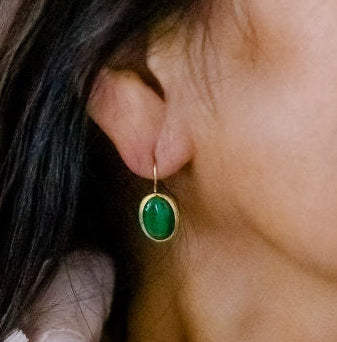 Two women hugging, one wearing a light pink scarf and turquoise earrings.