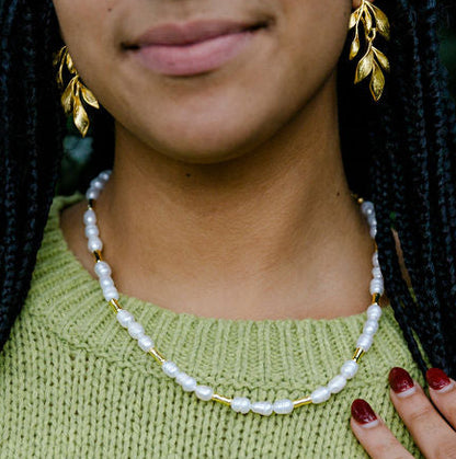 Woman wearing a green sweater with a blurred background and beautiful Pearl Beaded Necklace with Gold Detail