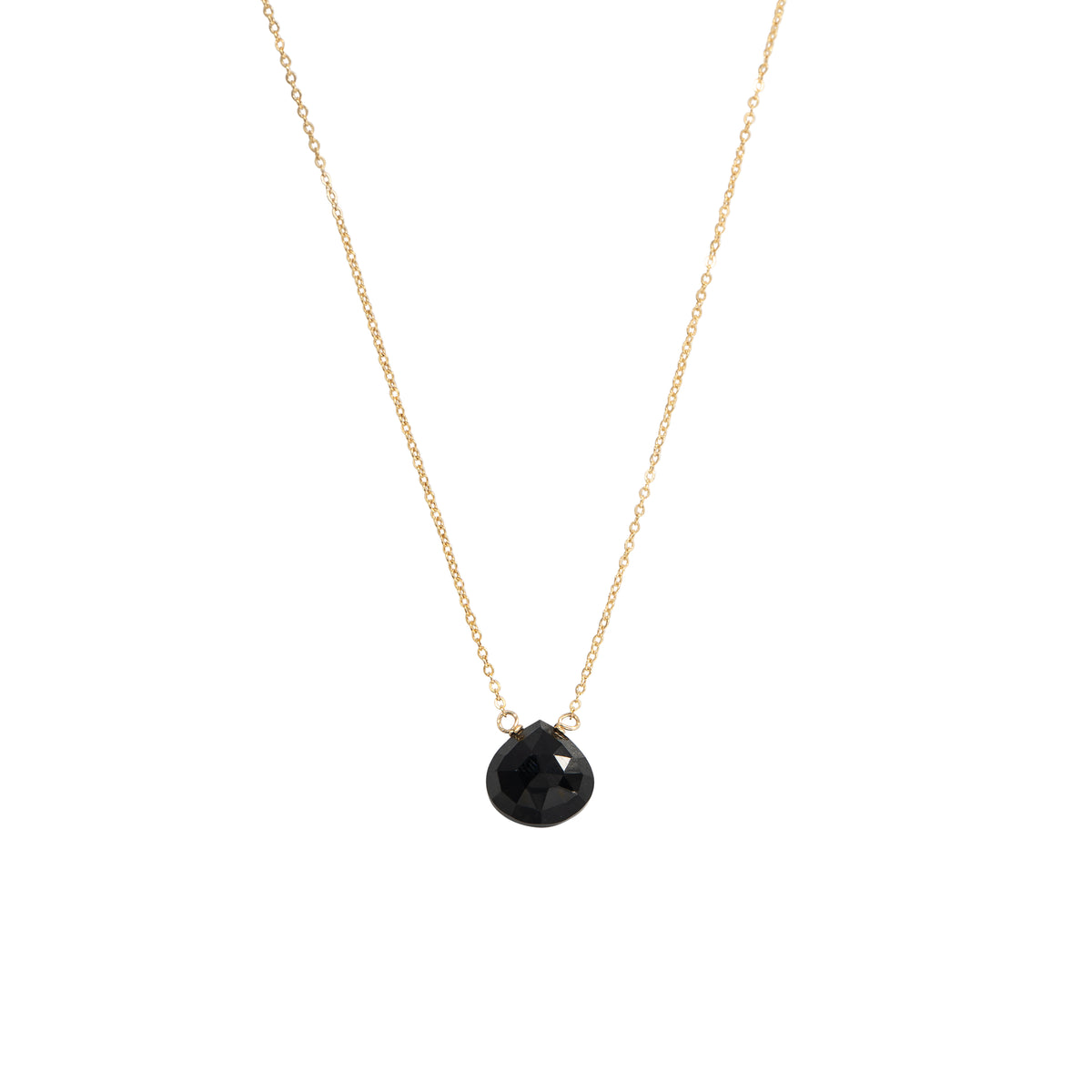 A delicate gold chain necklace featuring a small, faceted black teardrop pendant, shown against a solid white background.