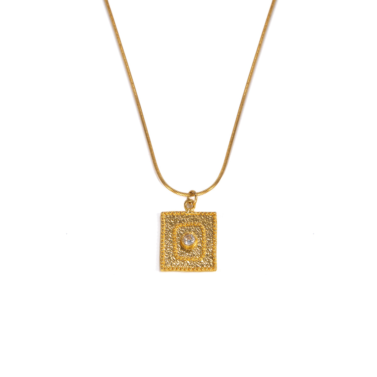 A gold square pendant necklace featuring a textured border and a central clear gemstone, suspended from a delicate gold chain against a plain white background.