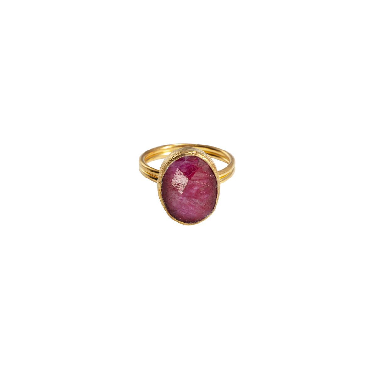 A gold ring featuring an oval-cut pinkish-red gemstone, set against a plain white background.