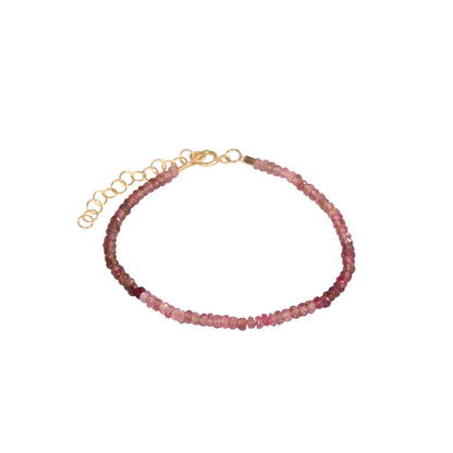 A delicate beaded bracelet featuring small, faceted pinkish-red beads strung on a gold-toned chain with an adjustable lobster clasp and extension links, shown against a plain white background.